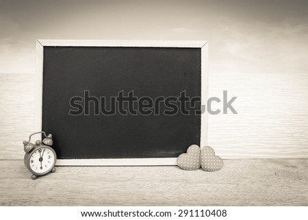 blackboard and red clock with two red hearts with blue ocean background