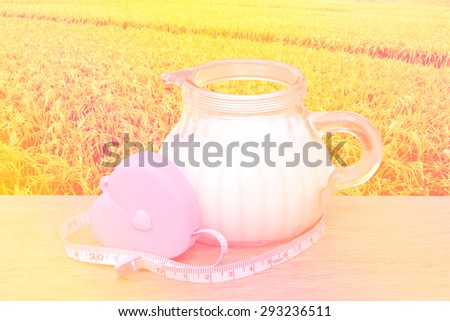 tape measure from heart case binding jug of milk with paddy field background with color filter