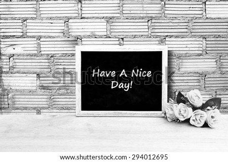 blackboard and bunch of roses on orange brick wall background in black and white tone
