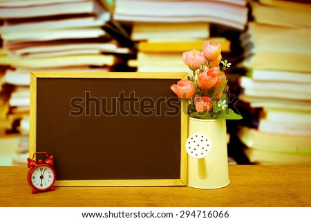 blackboard and watering pot vase with blur stacking book in vintage tone