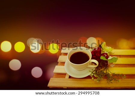 coffee and bunch of flower on the table with bokeh light in city night time background