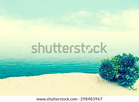 bunch of flower on sea sand with blur ocean background ,vintage tone