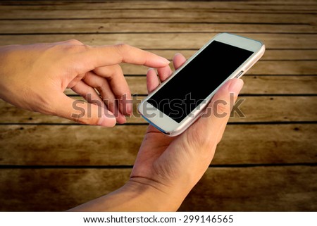 hand of man using mobile phone with blur wooden floor background