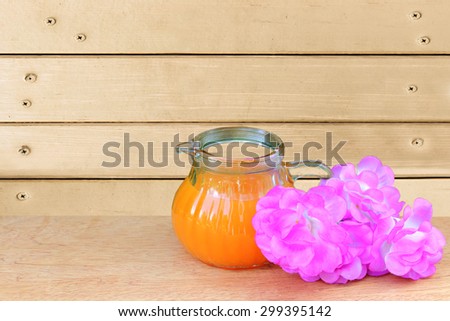 orange juice and pink flower with wooden wall and nails background