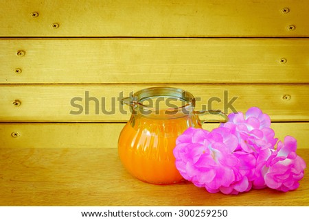 orange juice and pink flower with wooden wall and nails background  ,vintage tone