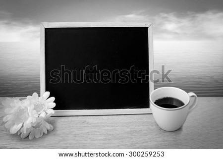 blackboard and coffee with blur ocean background ,black and white tone