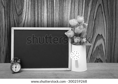 blackboard and watering pot vase with wooden wall background ,black and white tone