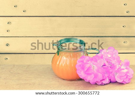 orange juice and pink flower with wooden wall and nails background ,vintage tone