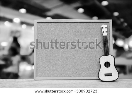 cork board and small guitar with blur restaurant background ,black and white tone
