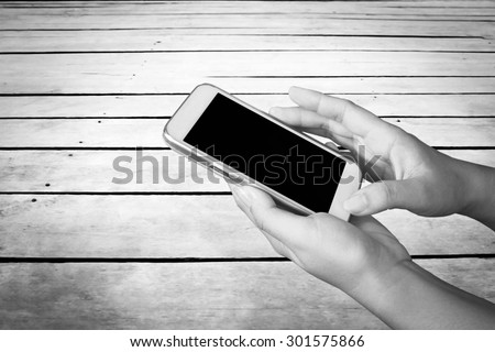 hand of child using mobile phone with wooden floor background ,black and white tone