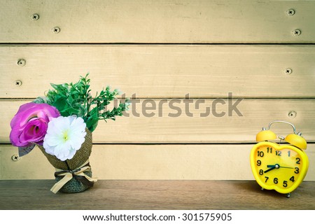 flower vase and clock with wooden wall and nails background ,vintage tone