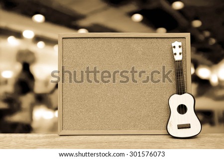 cork board and small guitar with blur restaurant background ,vintage tone