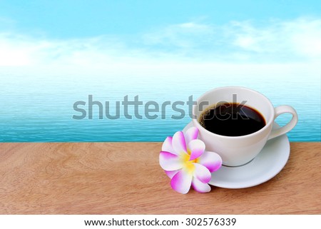 black coffee and purple flower with blur ocean background