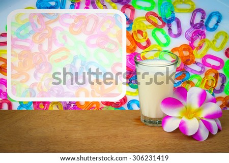 white frame with glass of milk and purple flower on plastic chain background