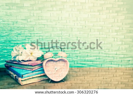 books and vintage clock on surface of woven from bamboo background  ,vintage tone