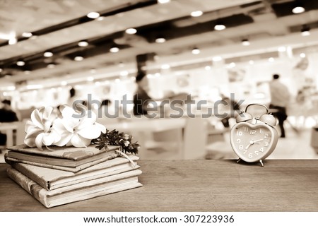 stacking books and blur clock with blur restaurant background ,vintage tone