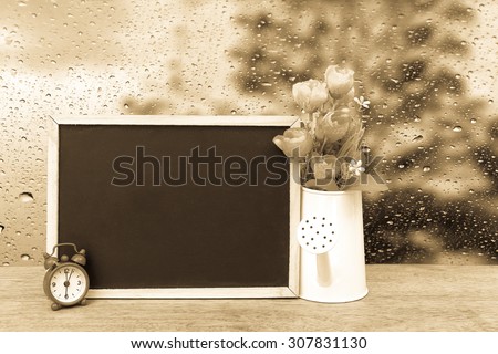 blackboard and watering pot vase with blur drop on mirror with dark tree background ,vintage tone