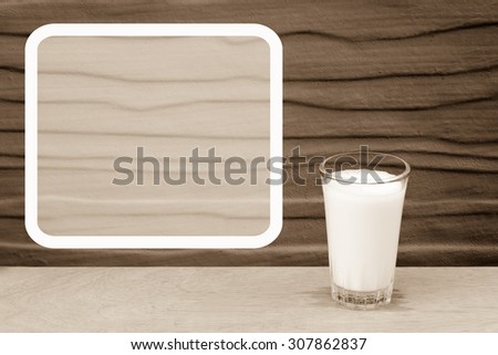 white frame with glass of cool milk on  grey wooden wall background  ,vintage tone