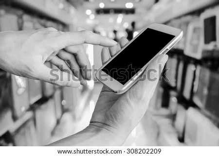 hand of man using mobile phone on blur shop background  ,black and white tone