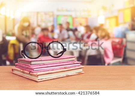 glasses on books with blur student in classroom background