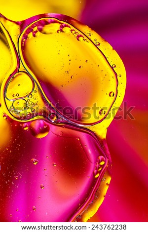 Colorful abstract shot of oil and water mixed together to show interesting bubbles patterns and shapes.  Ideal as vivid bright background, taken in portrait format.  Mostly pink and yellow.