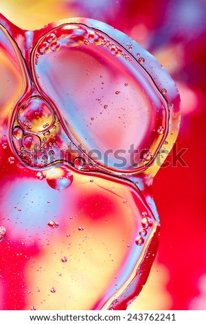 Colorful abstract shot of oil and water mixed together to show interesting bubbles patterns and shapes.  Ideal as vivid bright background, taken in portrait format.  Mostly red and pink.