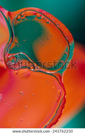 Colorful abstract shot of oil and water mixed together to show interesting bubbles patterns and shapes.  Ideal as vivid bright background, taken in portrait format.  Mostly green and orange.