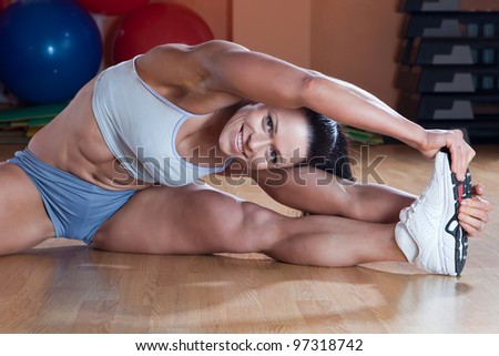 Beautiful athletic trainer shows examples of exercises in the gym