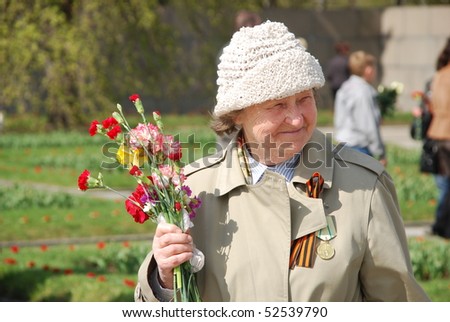 ST.PETERSBURG – MAY 9: An unidentified woman holds flowers for veterans at the Piskaryovskoye cemetery on May 9, 2009 in St.Petersburg. About 500,000 victims of the Nazi regime are buried there.