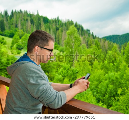 Young man using mobile phone. Mountains. Communication concept. Freedom. Vacation. Technology.