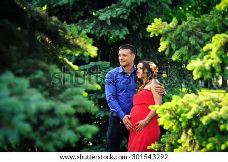 Happy pregnant woman and her husband in the park