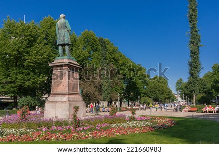 Helsinki, Finland - July 6, 2014: Summer atmosphere in the Esplanade Park. Statue of Johan Ludvig Runeberg in the foreground.