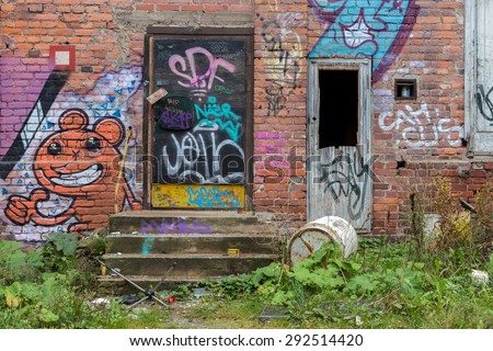 Tampere, Finland - September 26, 2014: Closed doors of a partly abandoned industrial building with graffiti on the wall.