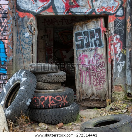 Tampere, Finland - October 23, 2014: Old tires in front of a broken door at an abandoned factory. Graffiti on the walls.