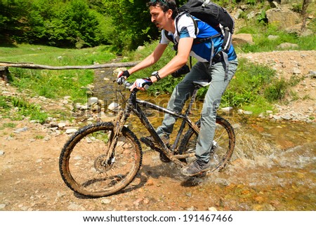 man crossing a creek on mountain bike