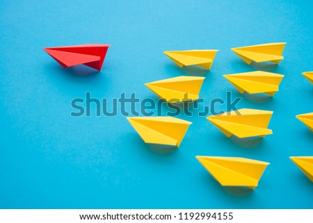 Leadership concept. Red paper plane origami leading among small yellow planes on blue background. Leadership skills need for top management in organization, company ex: supervisor, manager, CEO, CFO.
