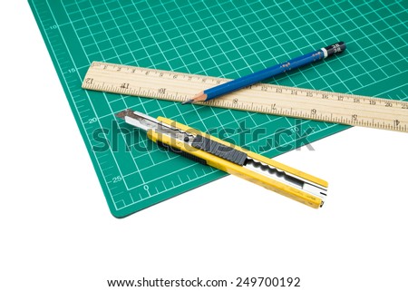 A wood ruler, cutter, cutting mat, pencil isolated over a white background