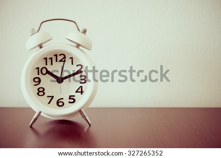 White alarm clock on wood table - retro effect style
