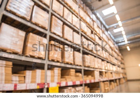 Abstract blurred boxes on rows of shelves in big modern warehouse background