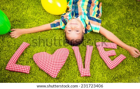 Boy lying on the carpet with the letters. Love.