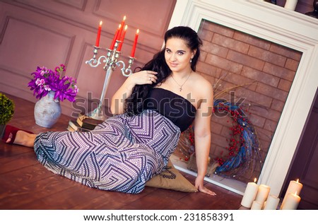 pregnant woman sits in a decorative fireplace