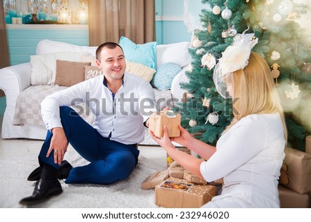 the man gives a Christmas gift to his beloved girl in the living room around the Christmas tree