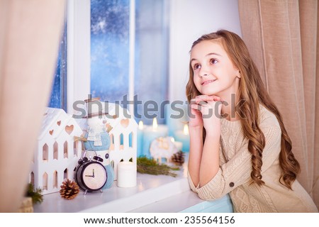 girl stands in a snowy window