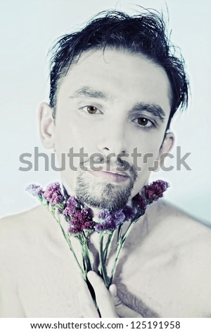 Face of young man with purple flower on light background