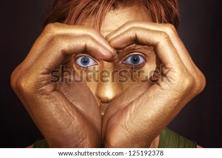 man's face with her hands folded in the shape of a heart closeup