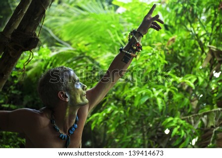 Portrait of adult man with theatrical ethnic makeup against the rainforest