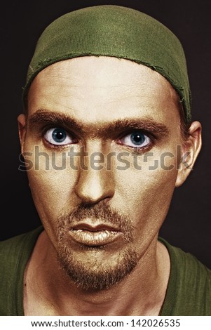 young attractive blue-eyed men with gold makeup in green headscarf closeup