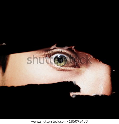 Scary eye of a man spying through a hole in the wall closeup