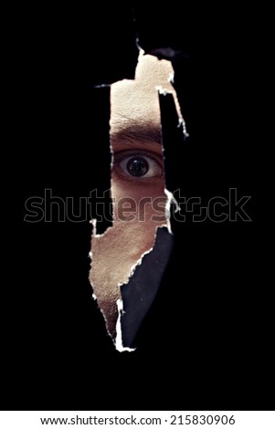 Scary eye of a man spying through a hole in the wall closeup
