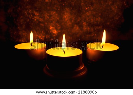 Three candles against a dark background